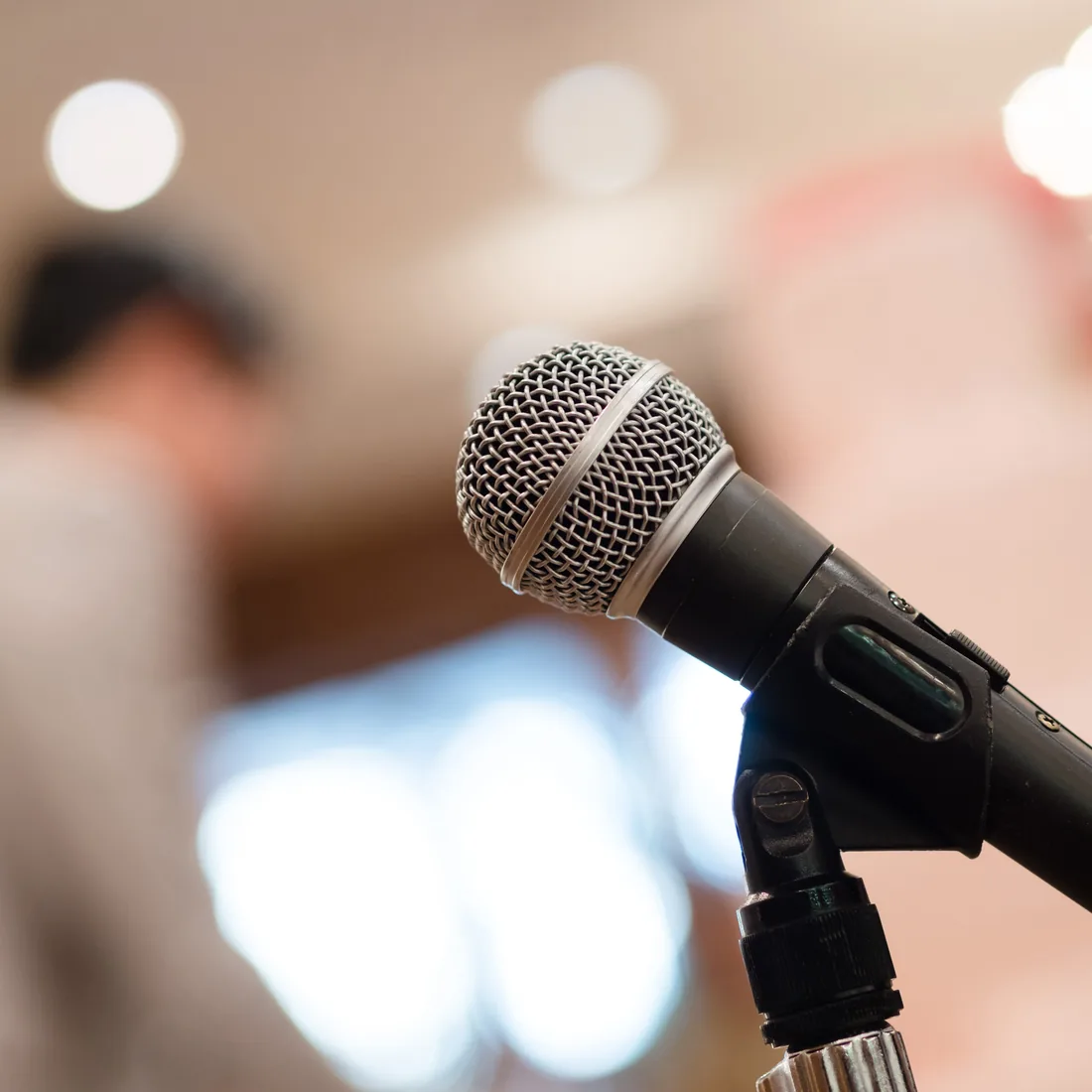 A microphone ready for a keynote, soft stage light behind